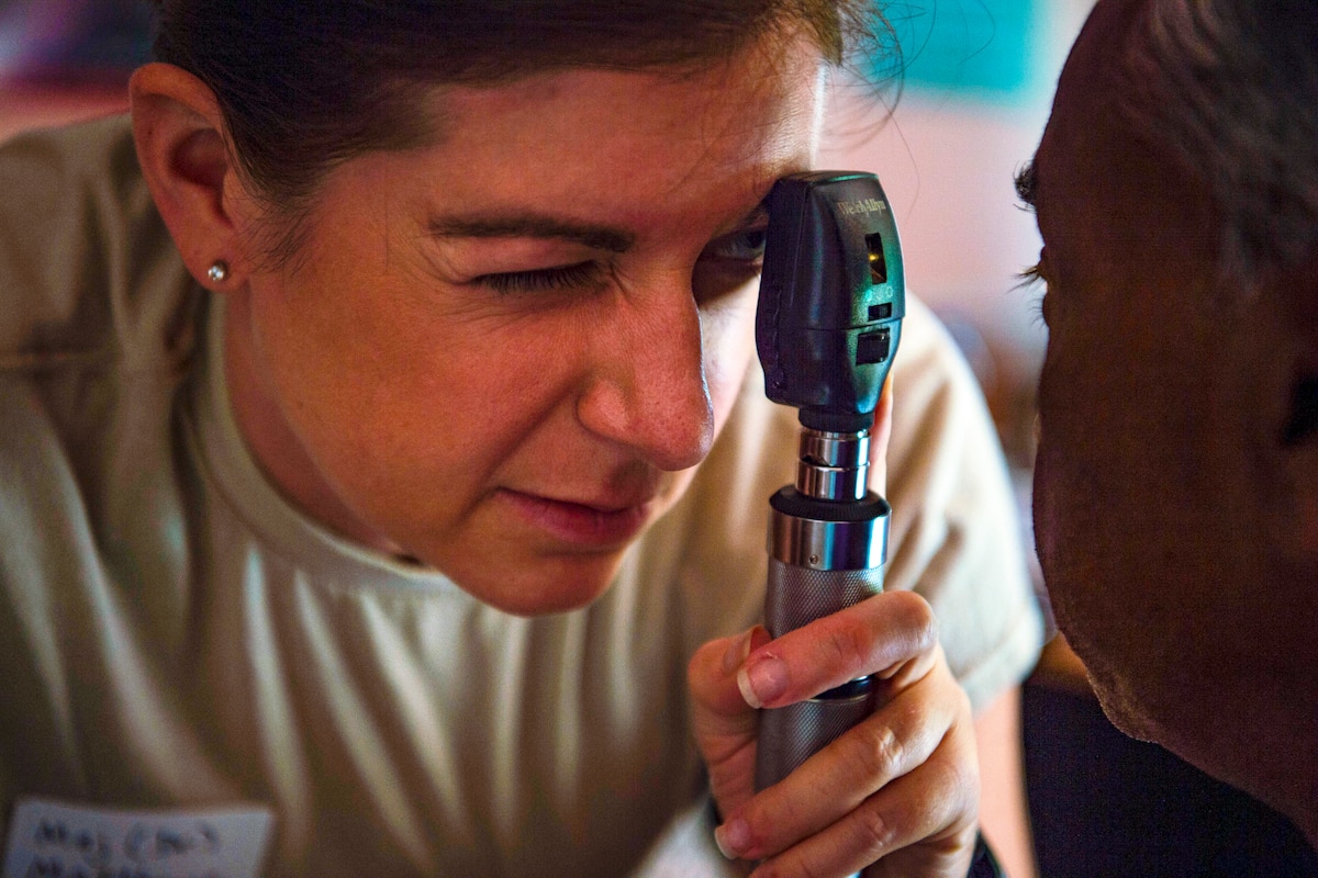 An airman examines a patient's eye