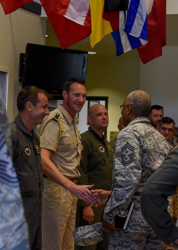 CMSgt. Jack Johnson Jr. goes down the line of NATO pilots, he smiles as he now shakes the hand of the German pilot who smiles back.