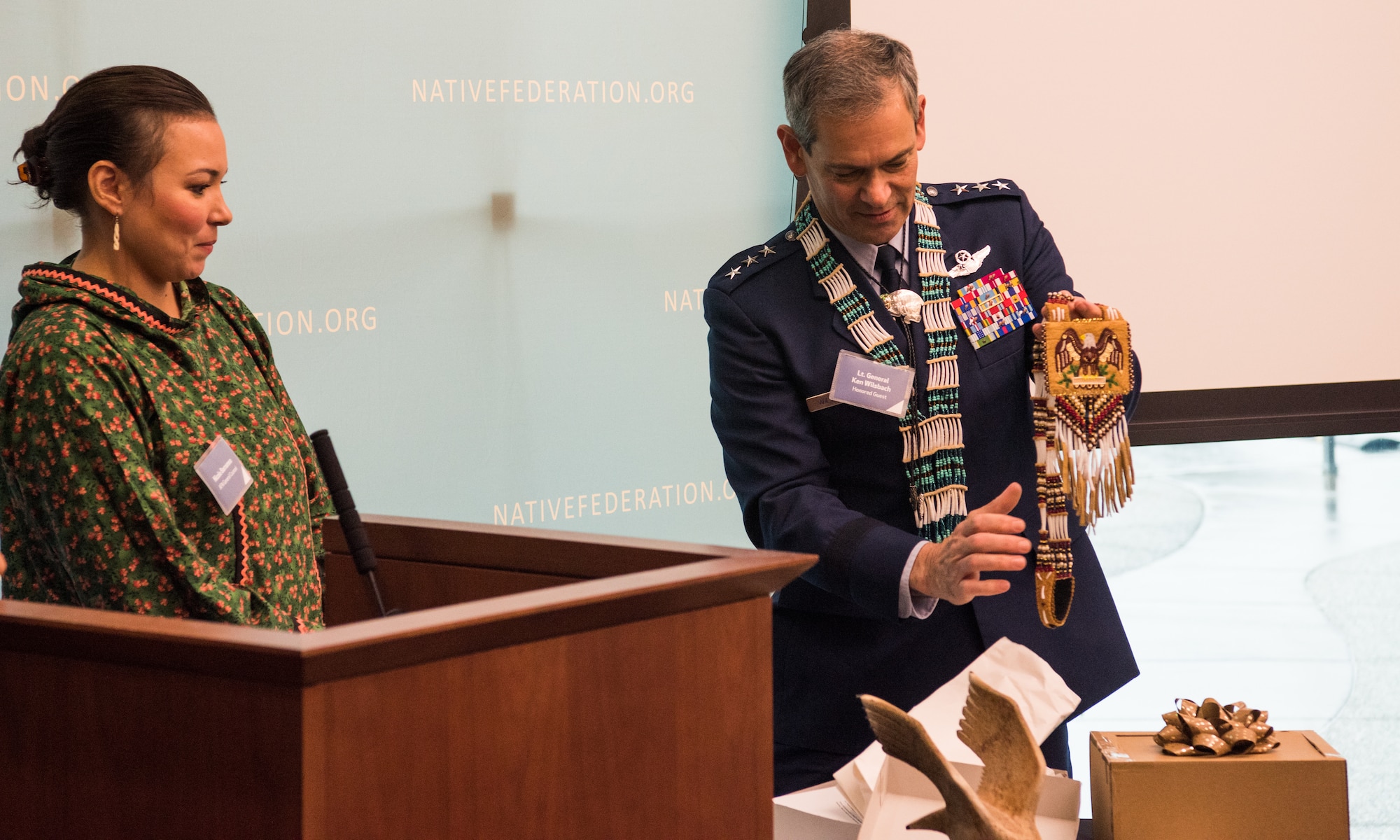 U.S. Air Force Lt. Gen. Ken Wilsbach, commander of Alaskan NORAD Region, Alaskan Command and Eleventh Air Force, accepts a gift from Nicole Borromeo, Alaskan Federation of Natives council member, during a Native Alaska naming ceremony at the Fireweed Convention Center in Anchorage, Alaska, Aug. 21, 2018. AFN hosted the unique event honoring Wilsbach for his service and involvement with Native Alaskan communities during his tenure in Alaska. It marked the first time in Alaska Native history a U.S. Armed forces general officer was given multiple Native names.