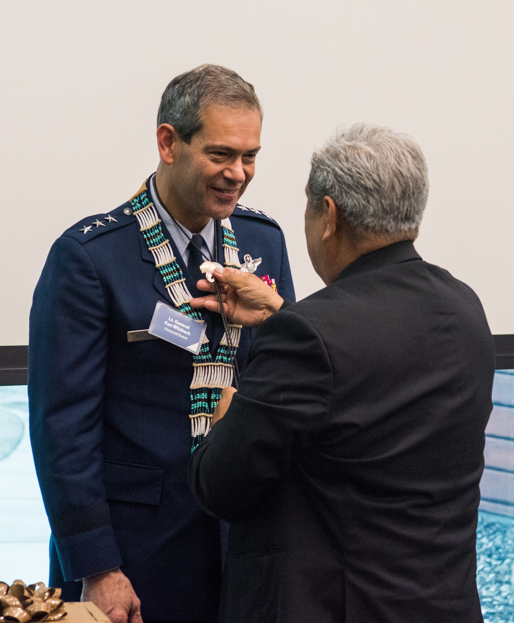 An Alaskan Federation of Natives council member presents a bolo tie to U.S. Air Force Lt. Gen. Ken Wilsbach, commander of Alaskan NORAD Region, Alaskan Command and Eleventh Air Force, during a Native Alaska naming ceremony at the Fireweed Convention Center in Anchorage, Alaska, Aug. 21, 2018. AFN hosted the unique event honoring Wilsbach for his service and involvement with Native Alaskan communities during his tenure in Alaska. It marked the first time in Alaska Native history a U.S. Armed forces general officer was given multiple Native names.