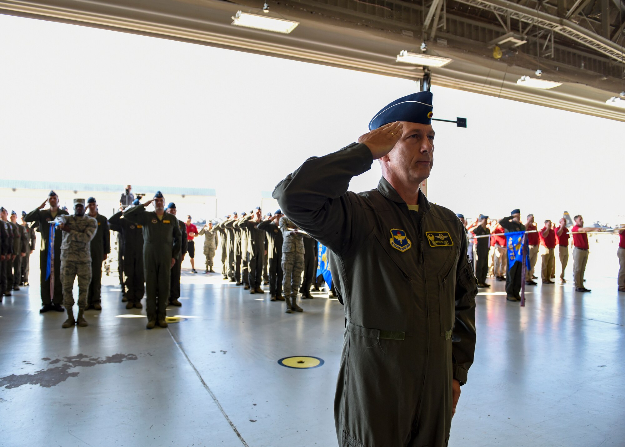 A pilot salutes in front of a squadron of pilots also saluting.