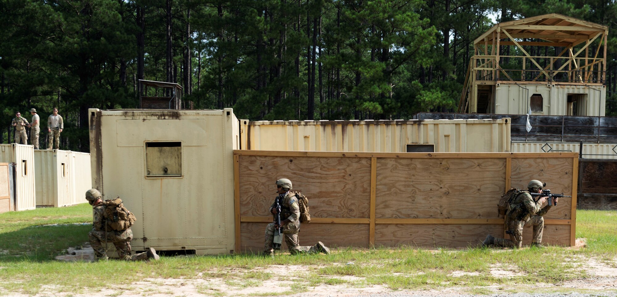 U.S. Air Force Airman 1st Class Evan Cooling, 20th Civil Engineer Squadron (CES) explosive ordnance disposal (EOD) apprentice, left, Senior Airman Elias Omar, 20th CES EOD journeyman, center, and Staff Sgt. Benjamin Leonard, 20th CES EOD journeyman prepare to assault a simulated hostile village while being observed at McCrady Army National Guard Base training area near Columbia, S.C., Aug. 23, 2018.
