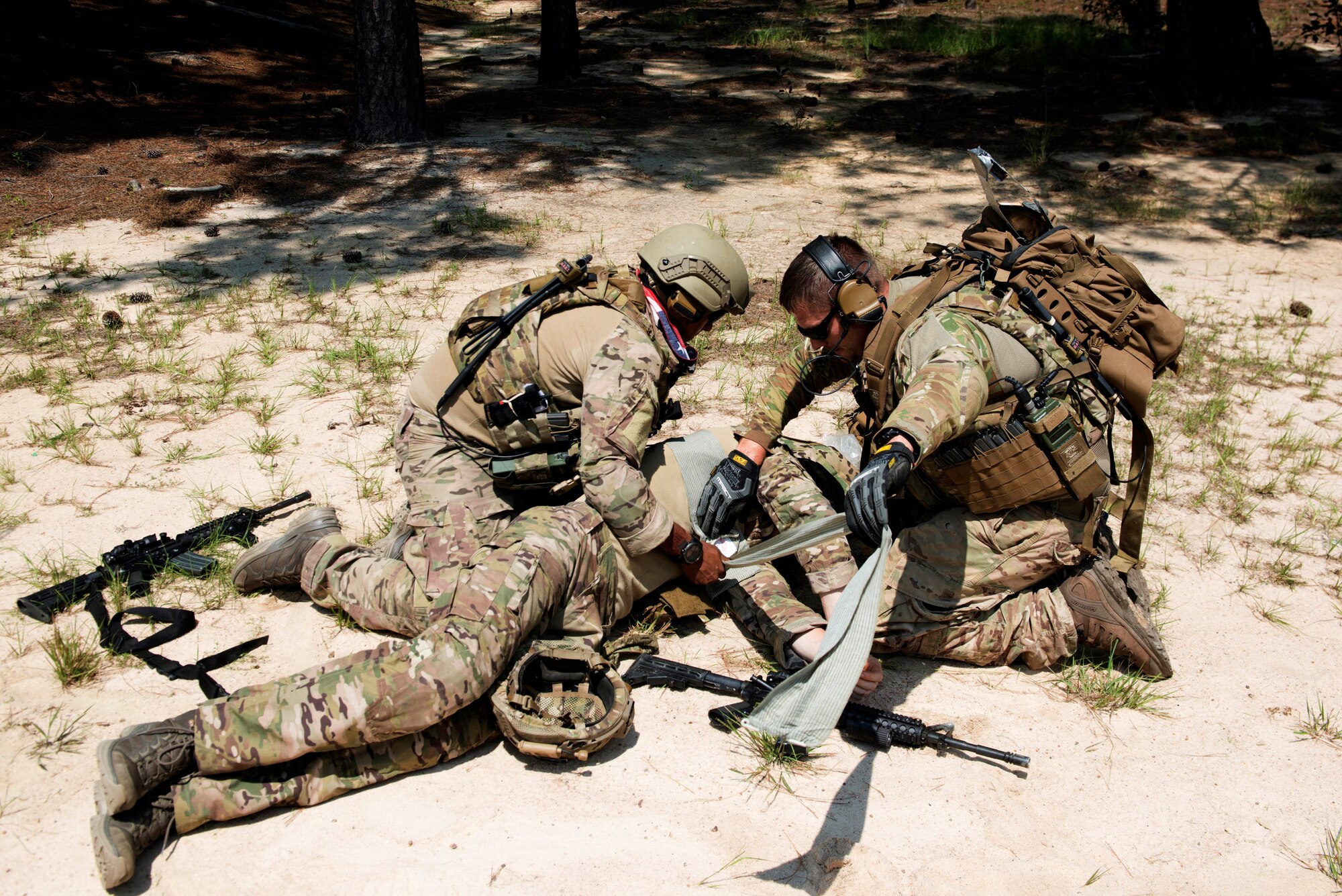 U.S. Air Force Senior Airman Elias Omar, 20th Civil Engineer Squadron (CES) explosive ordnance disposal (EOD) journeyman, left, and Staff Sgt. Wesley Clayton, 20th CES EOD craftsman, right, simulate life-saving treatment to Airman 1st Class Evan Cooling, 20th CES EOD apprentice, at McCrady Army National Guard Base training area near Columbia, S.C., Aug. 23, 2018.
