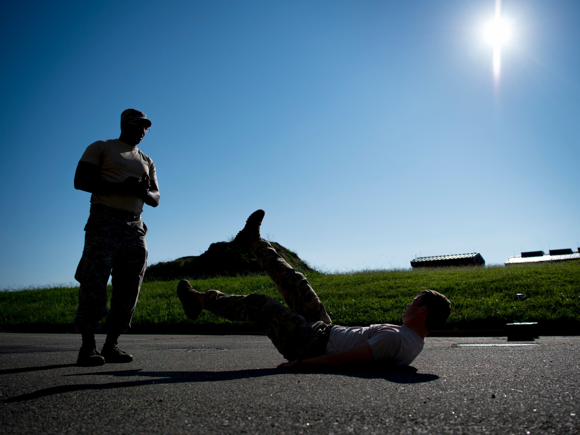 U.S. Air Force Tech. Sgt. Alexis Rice, Air Combat Command Directorate of Logistics, Engineering and Force Protection NCO in charge of mission assurance, watches Senior Airman Jeffrey Lewis, 822nd Base Defense Squadron fire team leader, perform flutter kicks during a physical training test as part of Air Combat Command’s Defender Challenge team selection at Joint Base Langley-Eustis, Virginia, Aug. 24, 2018