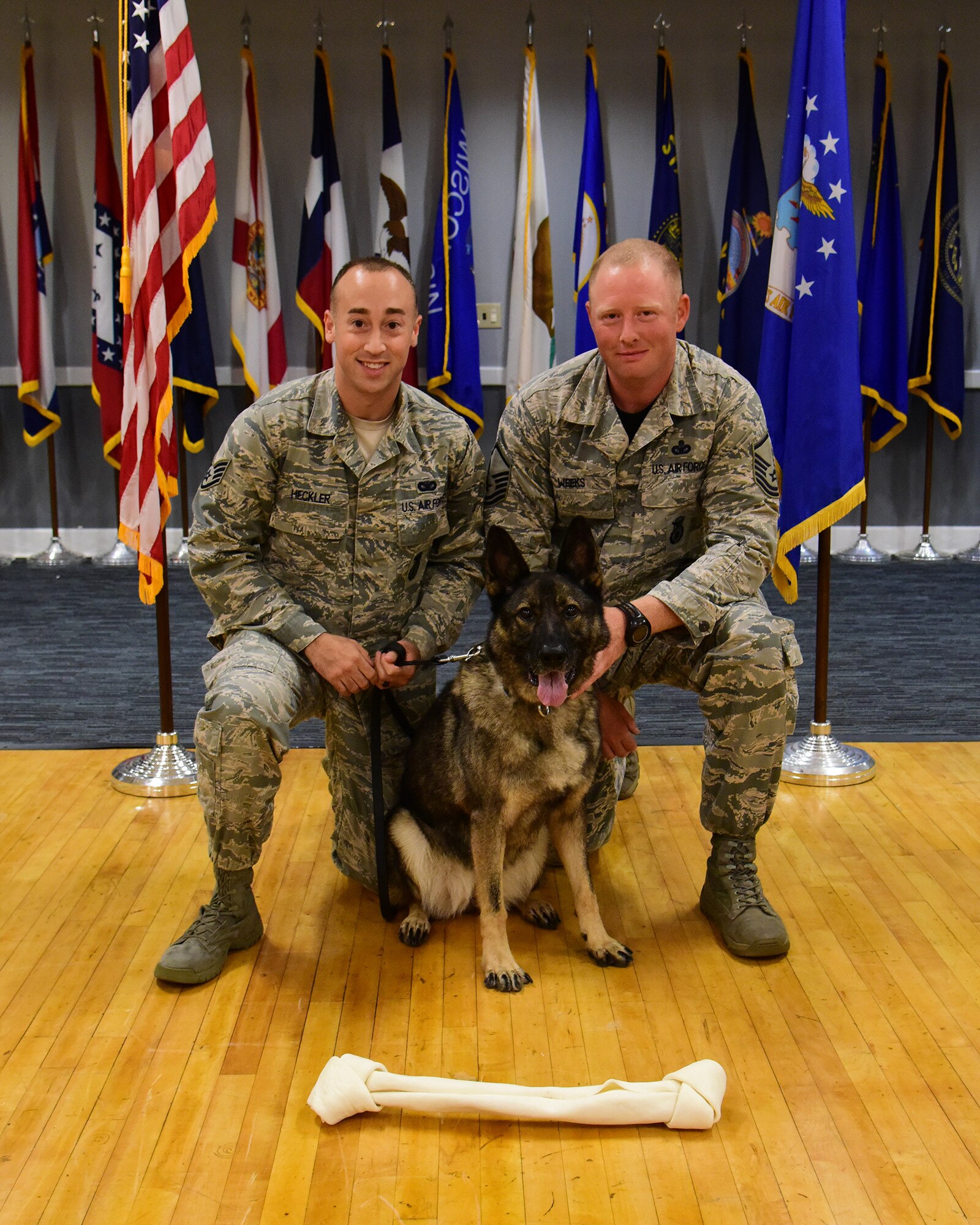 Staff Sgt. Nicholas Heckler, former 14th Security Forces Squadron military working dog handler, and Master Sgt. Dustin Weeks, 14th Security Forces Squadron acting first sergeant, kneel beside newly retired MWD Cherry, during Cherry’s retirement ceremony Aug. 24, 2018, on Columbus Air Force Base, Mississippi. Cherry retired after serving the Air Force for 10 years, and will go on to live with Heckler. (U.S. Air Force photo by Elizabeth Owens)