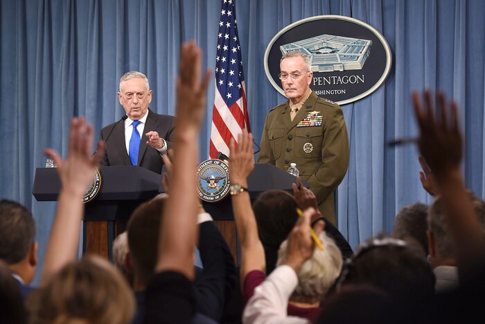 Defense Secretary James N. Mattis and Marine Corps Gen. Joe Dunford stand at lecterns facing reporters raising their hands.