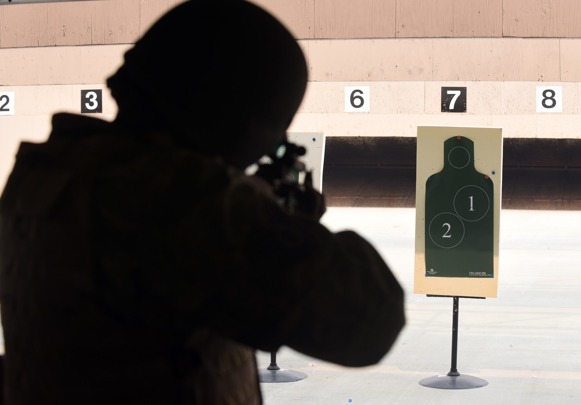 An Airmen points his M4 rifle at his target during a qualifying course