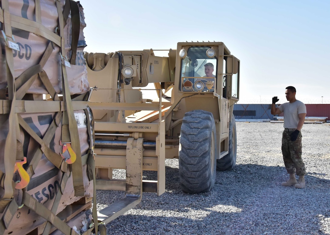 Air Force Master Sgt. Allan Reeves, Joint Special Operations Forces Support Detachment-K noncommissioned officer in charge of movements, guides Air Force Staff Sgt. Christopher Jensen, JSSD-K assistant NCOIC in charge of movements, as he uses a Skytrak 10K vertical reach forklift to move a pallet of Hesco barriers at an undisclosed location in Southwest Asia.