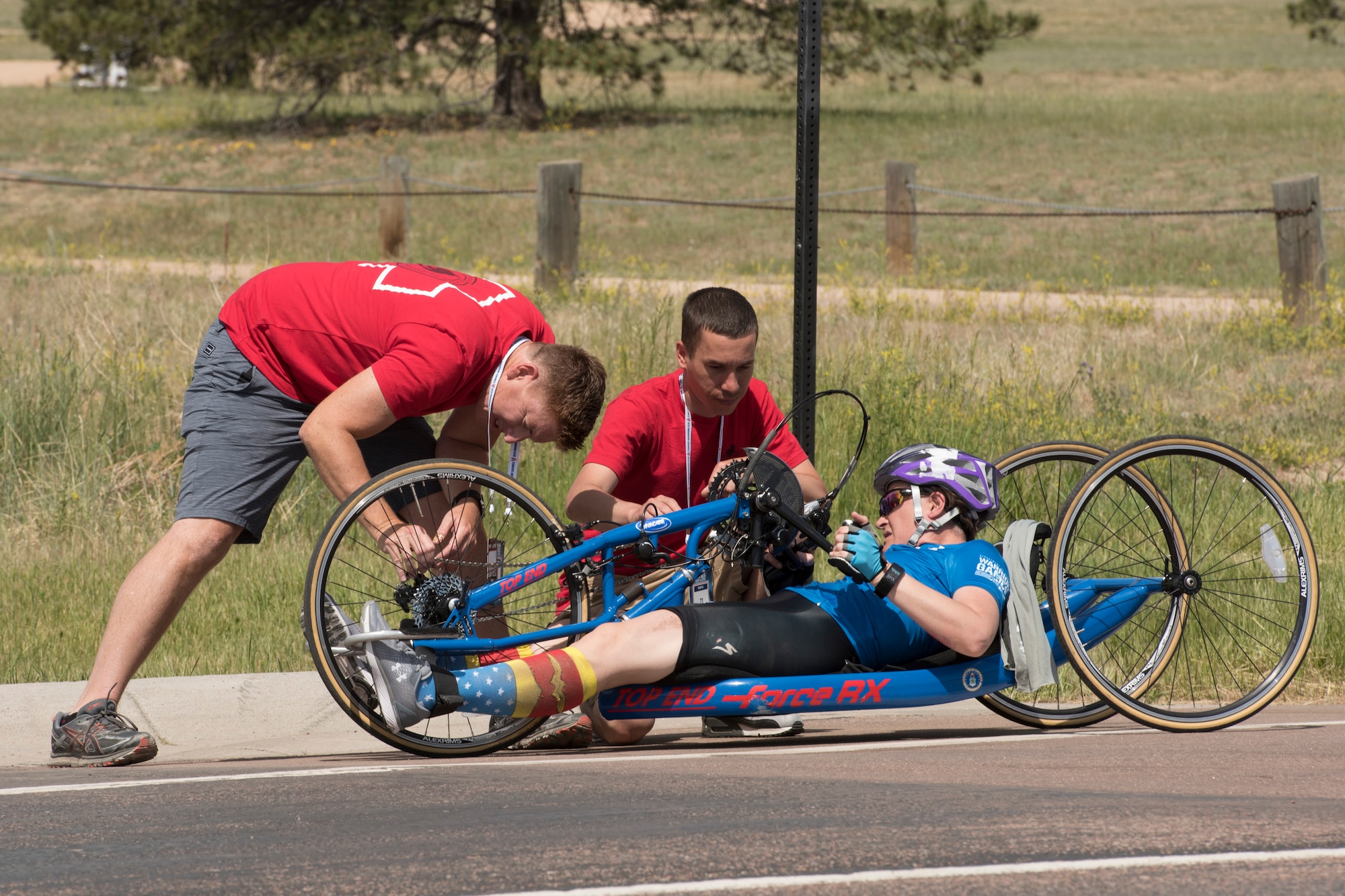 Master Sgt. Lisa Goad, Team Air Force athlete, observes as her bike is fixed after a crash during a hand-cycling race as part of the 2018 DoD Warrior Games at the U.S. Air Force Academy in Colorado Springs, Colo. on June 6. The Warrior Games are an annual event, established in 2010, to introduce wounded, ill and injured service members to adaptive sports as a way to enhance their recovery and rehabilitation. (DoD Photo by Roger L. Wollenberg)