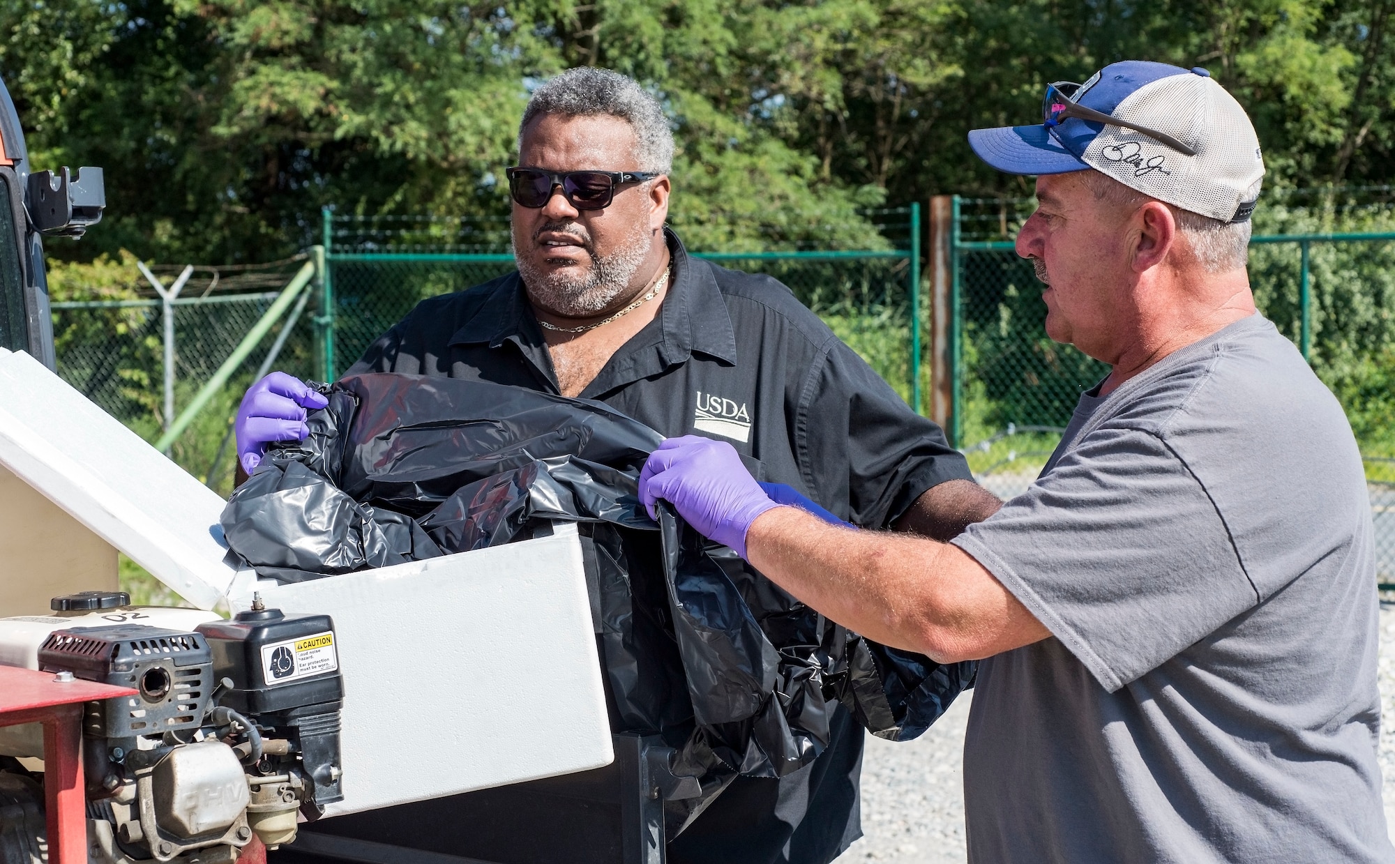Darryl Moore (left), U.S. Department of Agriculture Animal and Plant Health Inspection Service Plant Protection and Quarantine representative and state plant health director, and Kenneth Barnes, 436th Civil Engineer Squadron pest management section supervisor, unpack approximately 500 frozen dead Japanese beetles Aug. 9, 2018, at Dover Air Force Base, Del. The base was selected by the USDA as a test site for Japanese beetle population reduction by introducing a single cell, fungal-like pathogen to reduce the fecundity or reproductive capability of the beetle. (U.S. Air Force photo by Roland Balik)