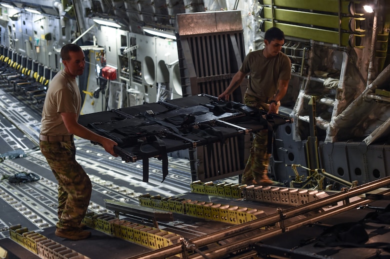 U.S. Air Force Tech. Sgt. Drew Czarnecki, left, and Staff Sgt. Raymond Sandoval, both 7th Airlift Squadron loadmasters, stow the disassembled part of seat away inside a C-17 Globemaster III during Exercise Predictable Iron at Pope Field, N.C., Aug. 23, 2018. Over the course of three days, Czarnecki, Sandoval and other Airmen helped drop 1,005 paratroopers during the exercise.  (U.S. Air Force photo by Senior Airman Tryphena Mayhugh)