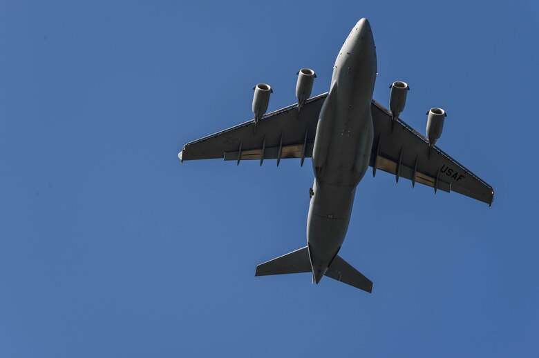 A C-17 Globemaster III from McChord Field, Wash., flies over the Normandy Drop Zone as paratroopers prepare to disembark the aircraft during Exercise Predictable Iron at Pope Field, N.C., Aug. 23, 2018. Airmen from the 62nd Airlift Wing worked alongside the Army to drop equipment and personnel during the exercise. (U.S. Air Force photo by Senior Airman Tryphena Mayhugh)