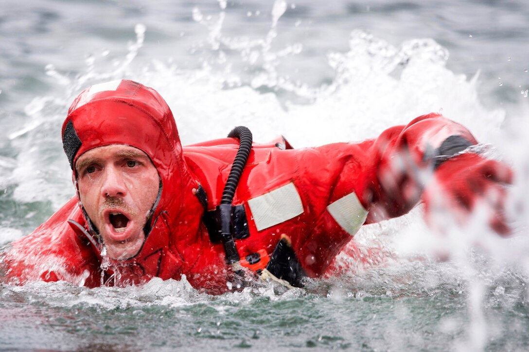 A Coast Guardsman gasps for air in frigid water during a survival swim.