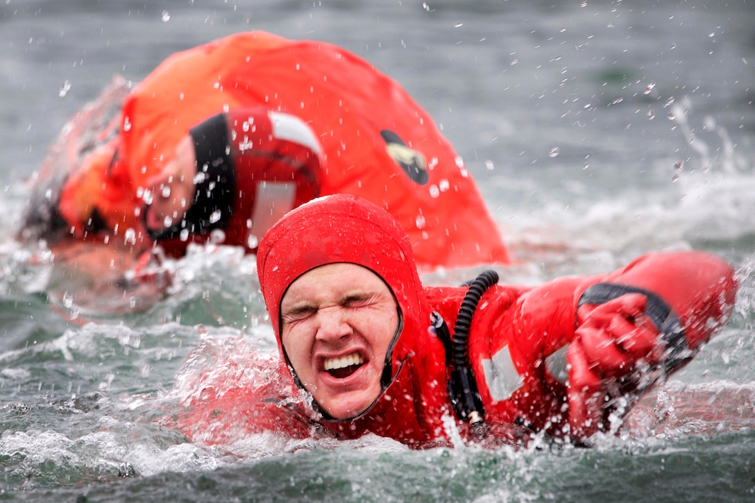 Coast Guardsmen swim in frigid water during a survival swim relay.