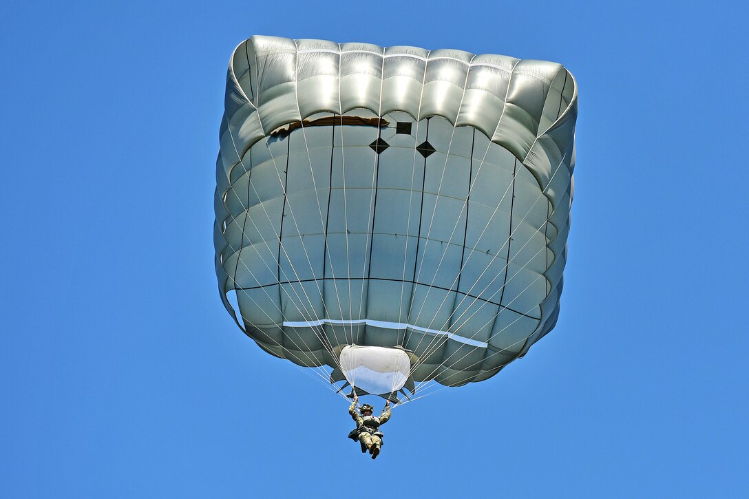 A U.S. paratrooper descends with full chute and prepares to land during airborne operations.