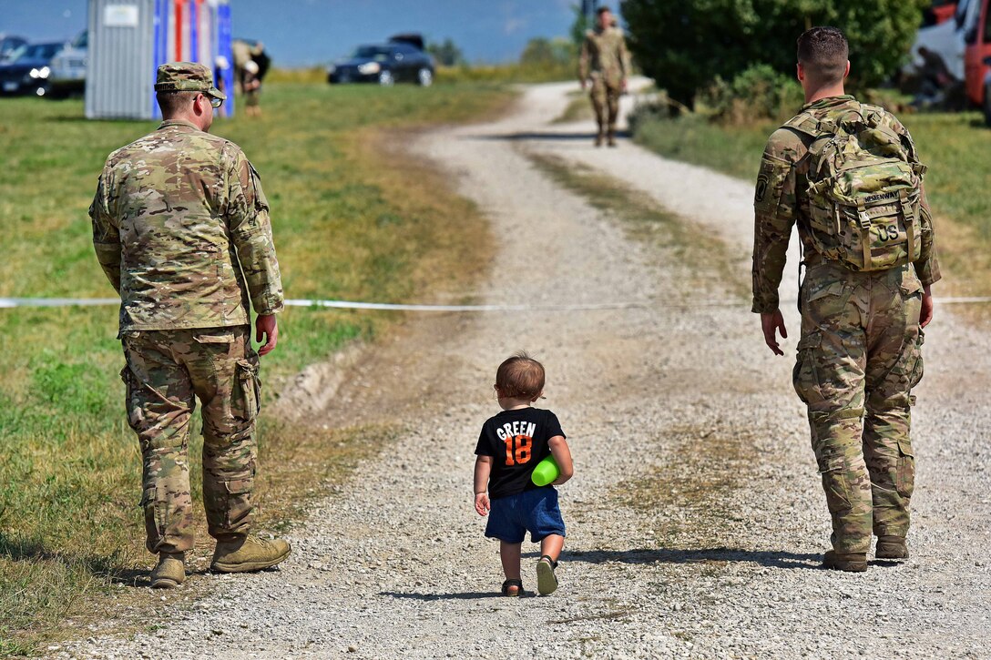 U.S. paratroopers are a followed by a little boy as they walk to the assembly are after conducting airborne operations.