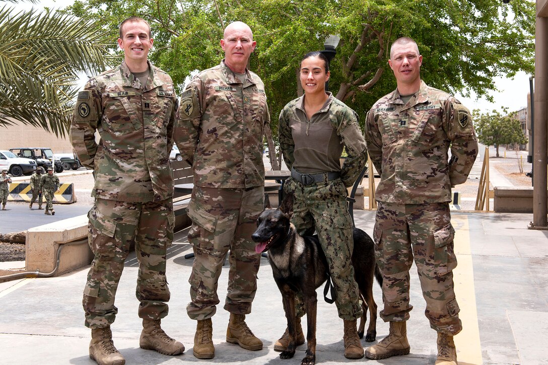 Service members and a military working dog pose for a photograph.