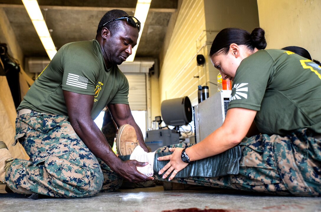 Hospital Corpsman 1st Class Hussein Taaha, left, applies a splint to the leg of Hospital Corpsman 1st Class Jesseca Anderson during Navy Medicine Augmentation Program pre-deployment training at Medical Simulation Training Center South, Okinawa, Japan, Aug. 25, 2018.  Medical personnel with 3rd Medical Battalion, 3rd Marine Logistics Group, worked with medical augments to prepare Role II medical facilities. Role II facilities provide a place for injured service members to be received while providing enhanced capabilities such as ultrasound, X-ray and surgery. Taaha, a native of Bronx, New York, is the leading petty officer at MSTC North. Anderson, a native of Boise, Idaho, is the en-route care program manager at MSTC North. (U.S. Marine Corps photo by Cpl. Joshua Pinkney)