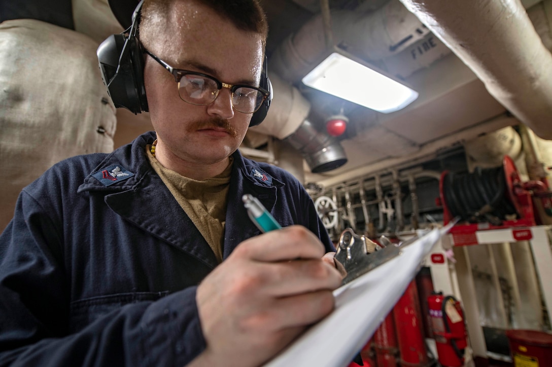A saliors records valve readings aboard the USS Essex.