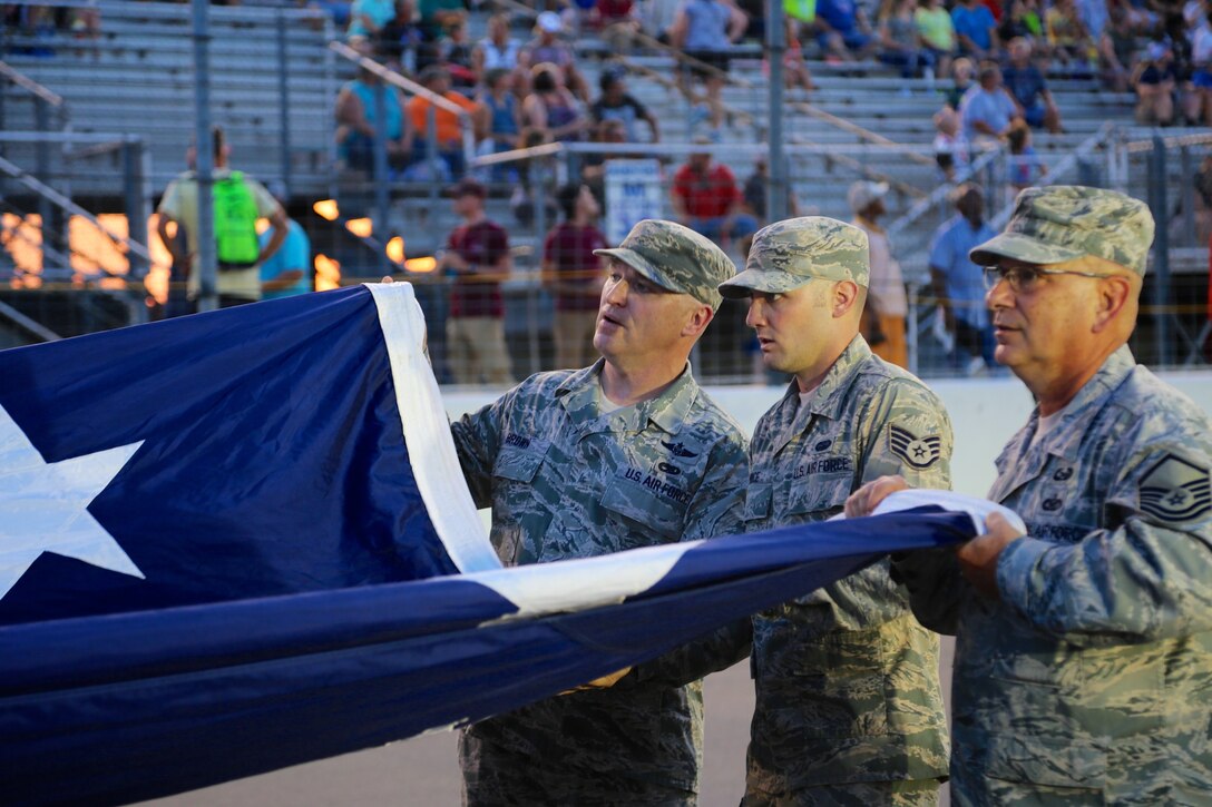 At far right, public affairs specialist and historian, Master Sgt. Gerald Sonnenberg, returned from retirement to help unfurl the American flag before the national anthem at Gateway Motorsports Park Aug. 25, 2018.  As part of the event, the 932nd Airlift Wing Maintenance Group commander, Col. Sharon Johnson, was recognized on stage with the Indy drivers at the Bommarito Automotive Group 500 race, held on a hot Saturday evening at Gateway Motorsports Park, Madison, Illinois. Johnson was an honored VIP to help kick off the IndyCar race which was won by Will Power.  He won the 248-lap race around the 1.25-mile Gateway Motorsports Park oval paved track in his #12 Chevrolet by 1.3117 seconds over second place finisher Alexander Rossi.  The 932nd Airlift Wing helped recruiting awareness and was represented by maintenance, medical, public affairs staff, retirees and operations personnel.  (U.S. Air Force photo by Lt. Col. Stan Paregien)