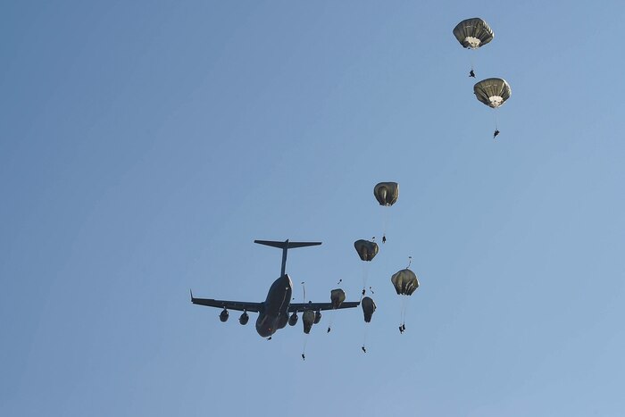 Paratroopers jump from an airplane.