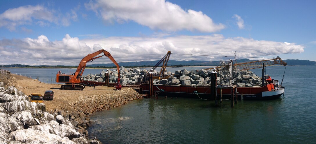 Heavy earth-moving equipment offload car-sized stones that will be used to repair Jetty A at the Mouth of the Columbia River