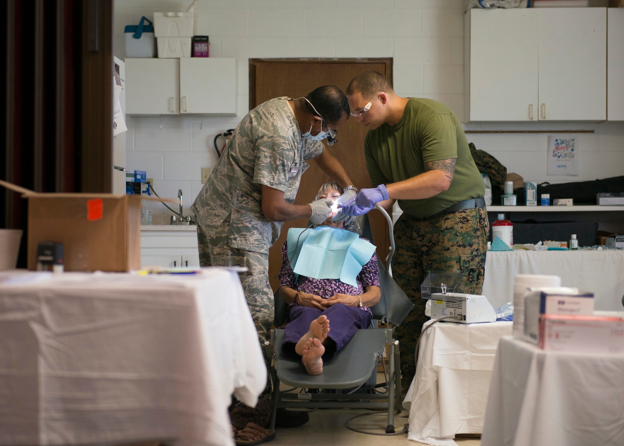 U.S. Air Force Col. Thaddeus Phillips, commander of the 2d Dental Squadron, gets assistance with a patient from U.S. Navy Petty Officer 2nd Class Brian O’Donnell, during Tropic Care Maui County 2018 in Lahaina, Hawaii, Aug. 12, 2018. (U.S. Air National Guard photo by 2nd Lt. Chelsea Clark)