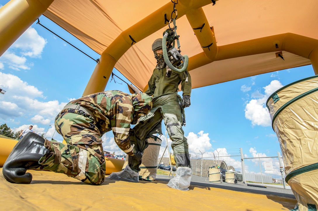 Two airmen work together to remove contamination gear.