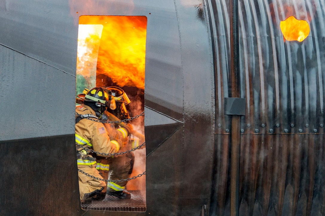 Firefighters battle a fire inside a training setup.