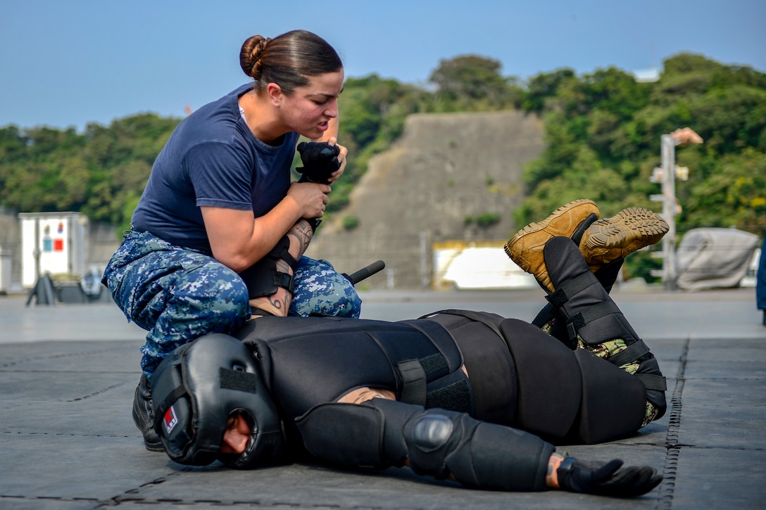 A sailor twists the arm of their training partner.