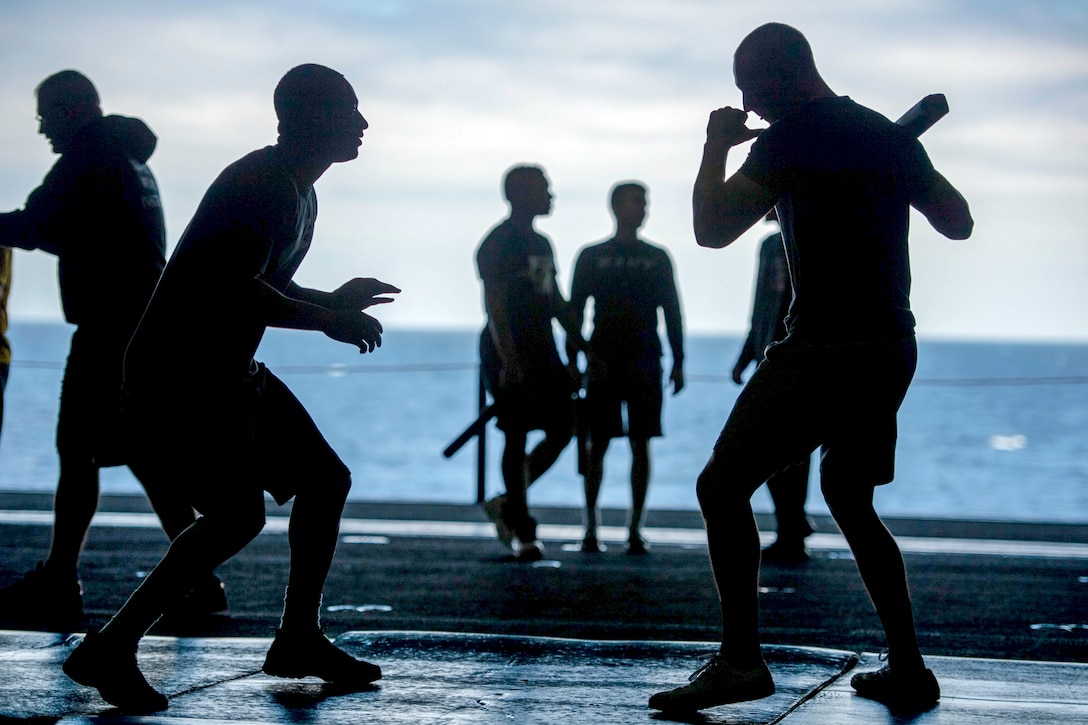 Sailors practice sparring with batons.