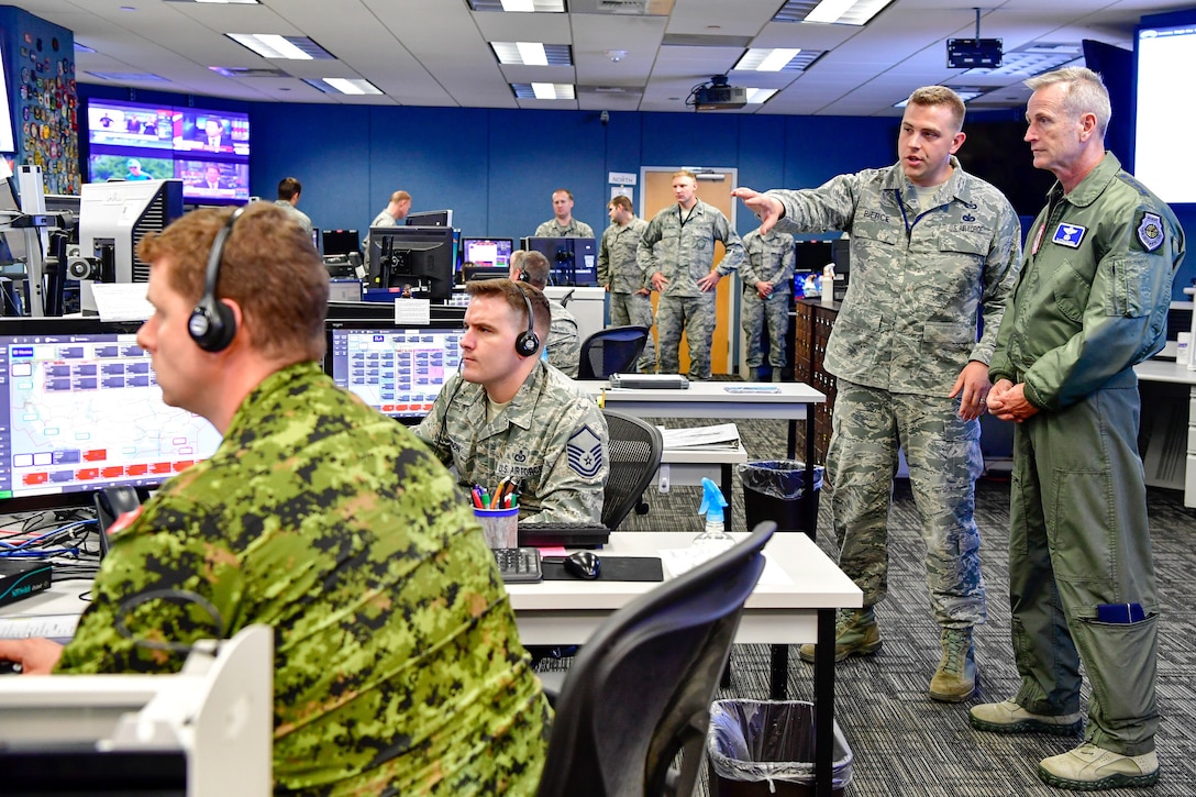 Service members sit in front of computers in an operations center.