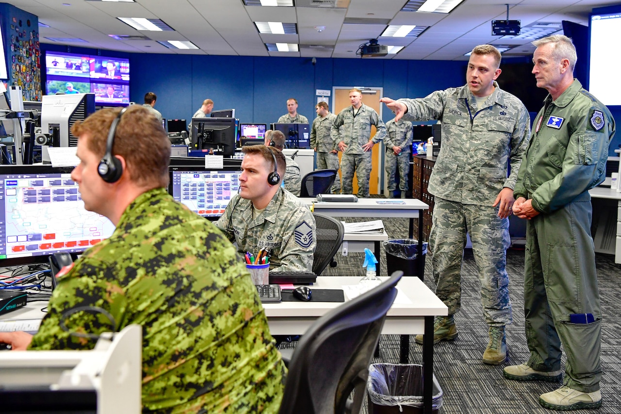Service members sit in front of computers in an operations center.
