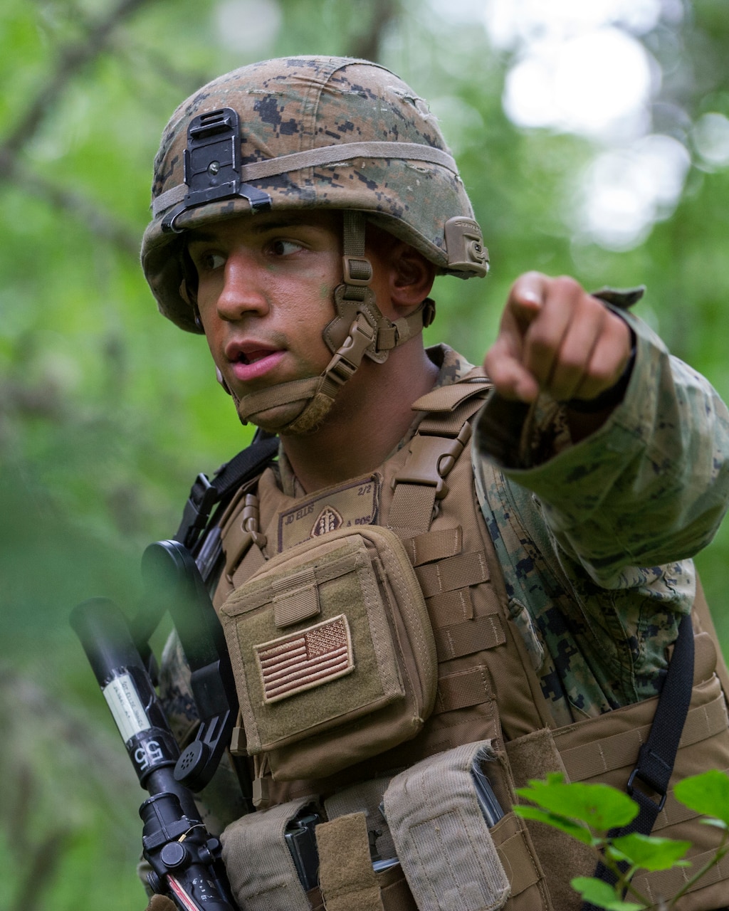 A Marine wearing combat equipment points toward the camera.