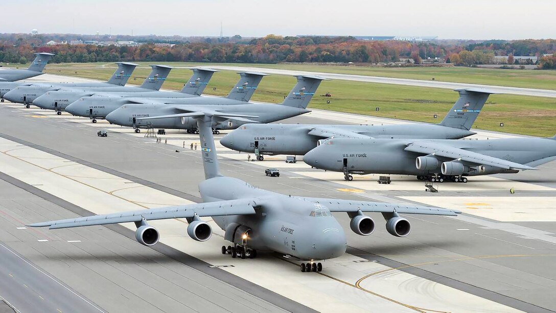 A C-5 Galaxy taxis past a line of C-5s sitting on the tarmac at Travis Air Force Base, California. DLA Aviation manages more than 74,000 parts for the C-5, which the Air Force is planning to keep in its arsenal until at least 2040.