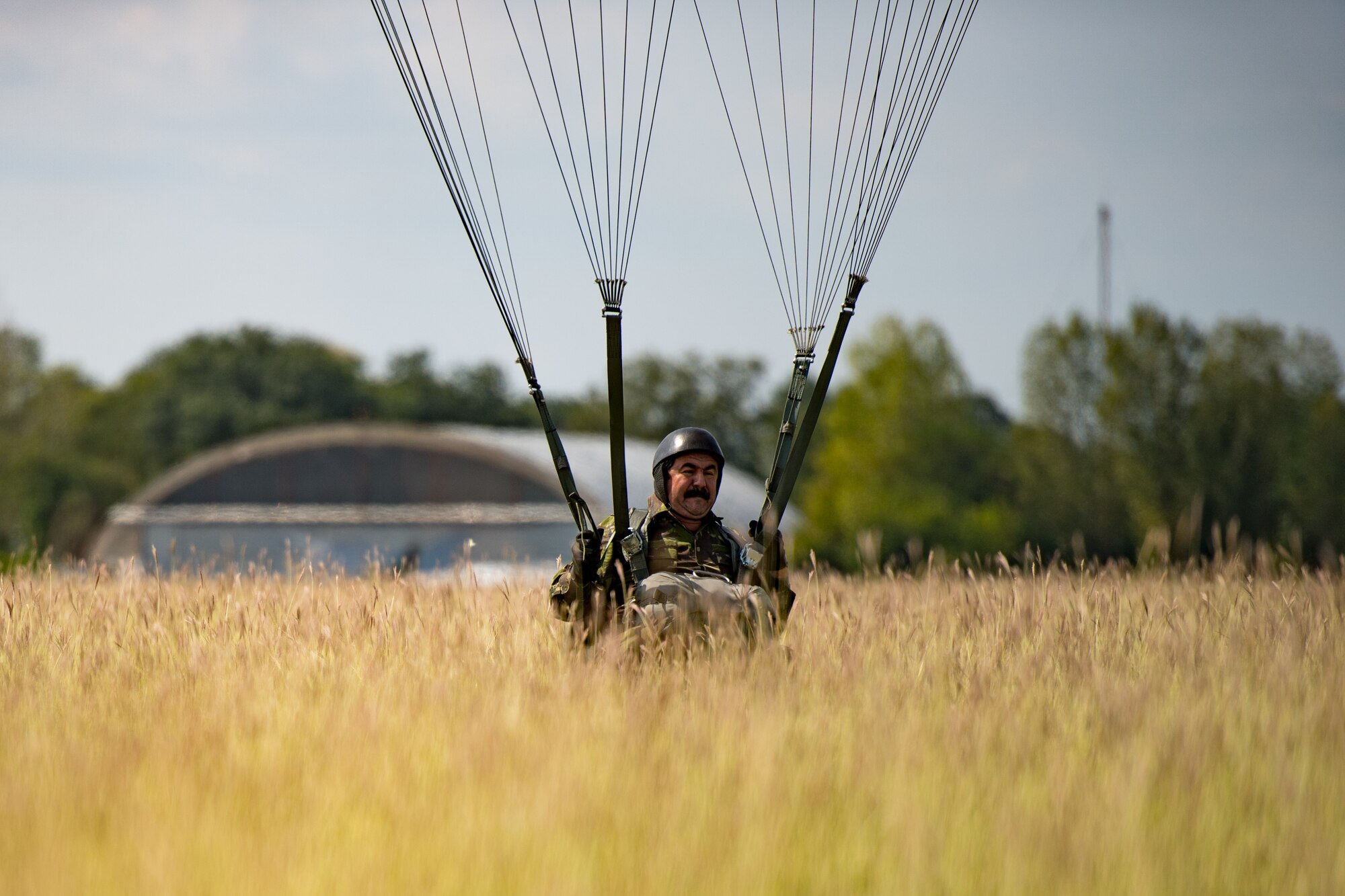 A Romanian air force paratrooper lands on a dropzone at Boboc Air Base, Romania, Aug. 23, 2018. The paratrooper jumped out of a U.S. Air Force C-130J Super Hercules aircraft as part of Carpathian Summer 2018, a bilateral training exercise designed to enhance interoperability and readiness of forces by conducting combined air operations with the Romanian air force. (U.S. Air Force photo by Senior Airman Devin Boyer)
