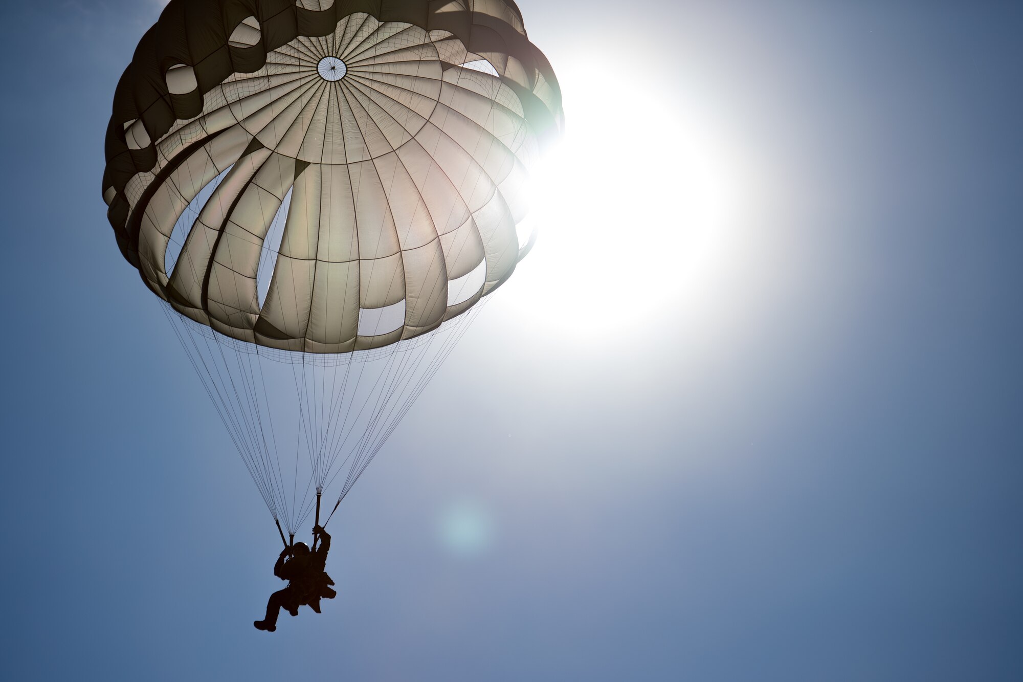 A Romanian air force paratrooper descends from the sky after jumping out of a U.S. Air Force C-130J Super Hercules aircraft assigned to the 37th Airlift Squadron, Ramstein Air Base, Germany, over Boboc Air Base, Romania, Aug. 23, 2018. The airdrops were part of exercise Carpathian Summer 2018, a bilateral training exercise designed to enhance interoperability and readiness of forces by conducting combined air operations with the Romanian air force. (U.S. Air Force photo by Senior Airman Devin Boyer)