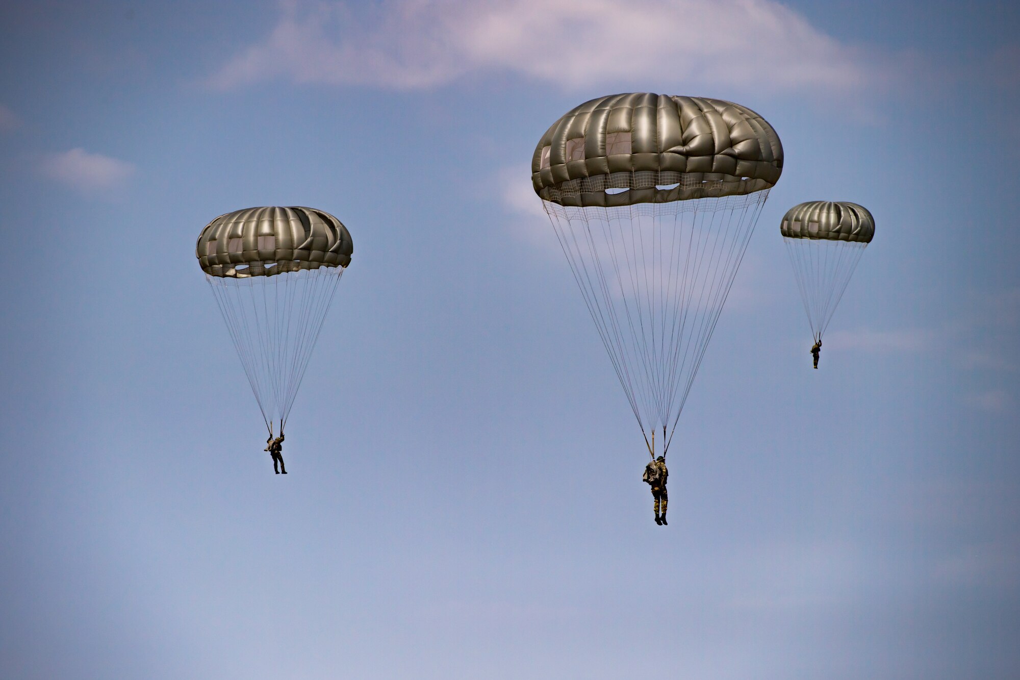 Romanian air force paratroopers descend from the sky after jumping out of a U.S. Air Force C-130J Super Hercules aircraft assigned to the 37th Airlift Squadron, Ramstein Air Base, Germany, over Boboc Air Base, Romania, Aug. 23, 2018. The airdrops were part of exercise Carpathian Summer 2018, a bilateral training exercise designed to enhance interoperability and readiness of forces by conducting combined air operations with the Romanian air force. (U.S. Air Force photo by Senior Airman Devin Boyer)