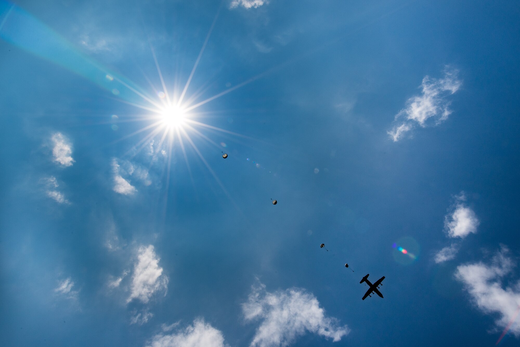 Romanian air force paratroopers descend from the sky after jumping out of a U.S. Air Force C-130J Super Hercules aircraft assigned to the 37th Airlift Squadron, Ramstein Air Base, Germany, over Boboc Air Base, Romania, Aug. 23, 2018. The airdrops were part of exercise Carpathian Summer 2018, a bilateral training exercise designed to enhance interoperability and readiness of forces by conducting combined air operations with the Romanian air force. (U.S. Air Force photo by Senior Airman Devin Boyer)