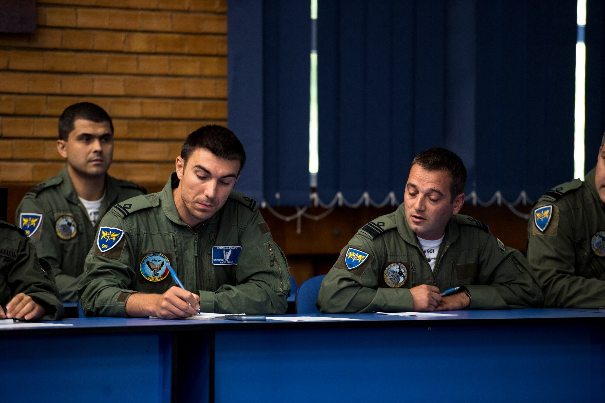Romanian air force personnel take notes during a brief for exercise Carpathian Summer 2018 on Otopeni Air Base, Romania, Aug. 22, 2018. During the brief, U.S. Air Force and Romanian air force personnel discussed objectives for the exercise. (U.S. Air Force photo by Senior Airman Devin Boyer)