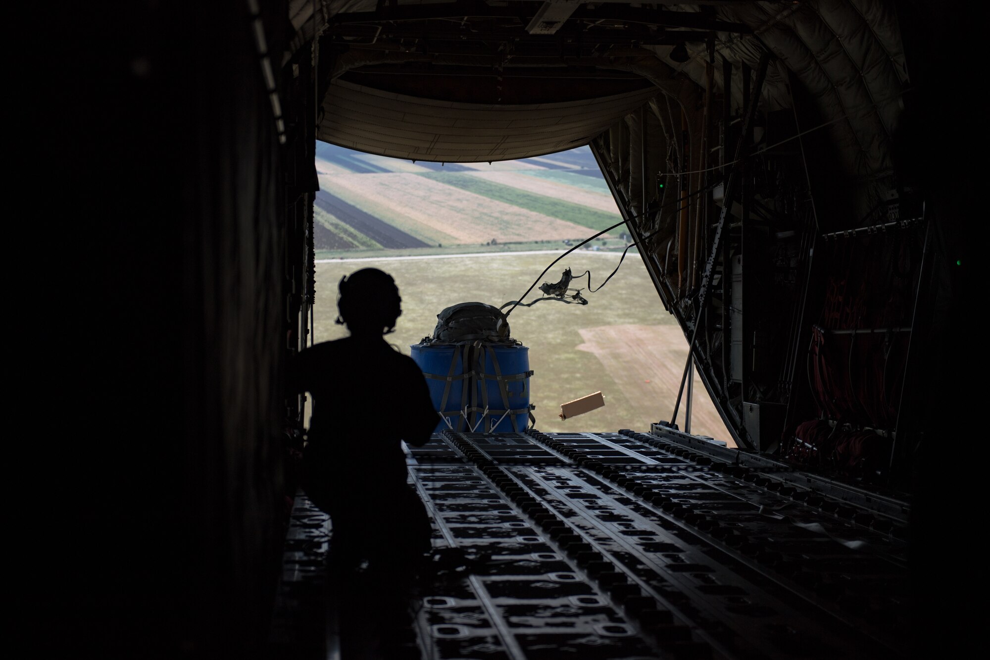 U.S. Air Force Staff Sgt. Sarah Meadows, 37th Airlift Squadron loadmaster releases a container delivery system with her wingmen during an airdrop over Boboc Air Base, Romania, Aug. 27, 2018. The CDS is a commonly used method for the aerial insertion of supplies for contingency operations. (U.S. Air Force photo by Senior Airman Devin Boyer)