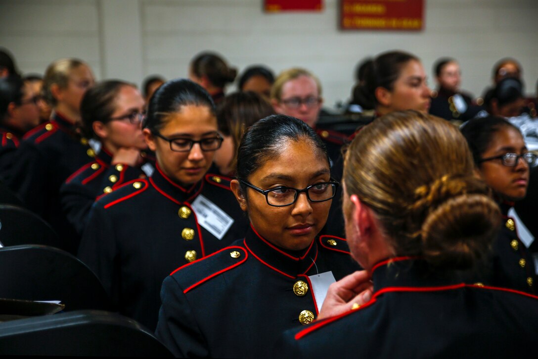 Marine Corps recruits try on navy blue coats with red piping.