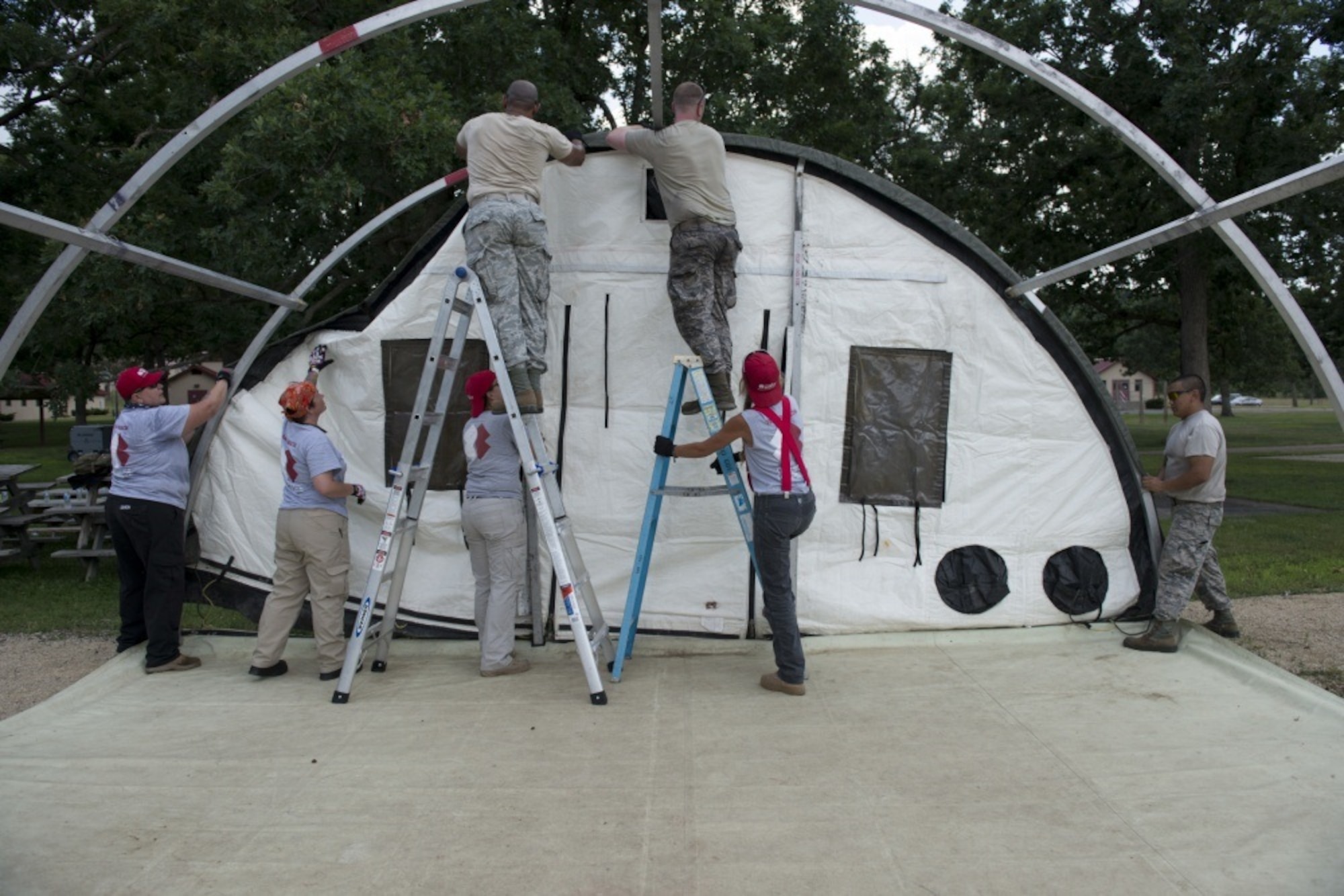 Members of the 103rd Civil Engineer Squadron and Team Rubicon work together to set up a tent, Sunday, July 15, 2018, during the PATRIOT North 18 Exercise, at Volk Field Air National Guard Base, Wis. The tent was used as a dining facility during the exercise. (Air National Guard photo by Tech. Sgt. Tamara R. Dabney)