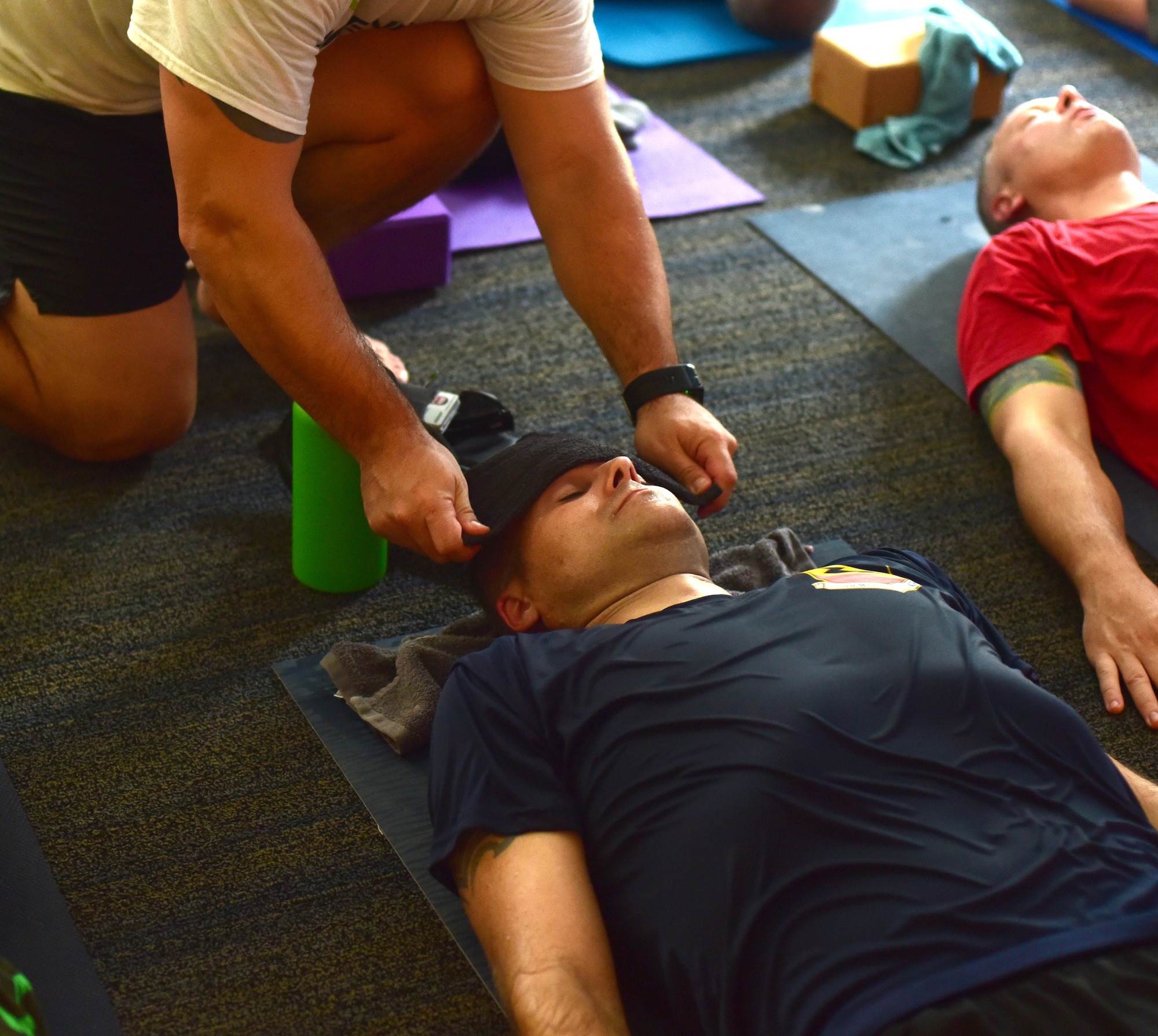 U.S. Air Force Master Sgt. Ramiro Villalobos, Paul W. Airey Noncommissioned Officer Academy instructor, puts warm cloths over his student’s eyes during a Tyndall Pacesetters yoga session at the Balfour Beatty Community Center on Tyndall Air Force Base, Florida, Aug. 22, 2018. Near the end of each session the students lay down and close their eyes to help clear their mind and reach a stage of inner peace. Villalobos teaches yoga for the group with the goal of providing a positive atmosphere of self-betterment through high-intensity training, yoga and run training. (U.S. Air Force photo by Senior Airman Cody R. Miller)