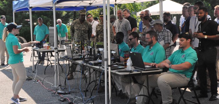 IMAGE: DAHLGREN (Aug. 7, 2018) – Kim Wendt – a Naval Surface Warfare Center Dahlgren Division (NSWCDD) software engineer – briefs military personnel and senior scientists and engineers about the Sly Fox Mission 23 demonstration known as the Autonomous Remote Tactical Engagement Multi-Domain Intelligence Swarm (ARTEMIS). Wendt was among seven junior scientists and engineers (less than two years out of college) who developed ARTEMIS to engage in enhanced ISR missions using unmanned ground vehicles (UGVs), artificial intelligence, and machine learning to detect targets efficiently and effectively. While the use of UGVs met the requirements set forth by Mission 23, the team envisions a more complex system that expands to the aerial domain.