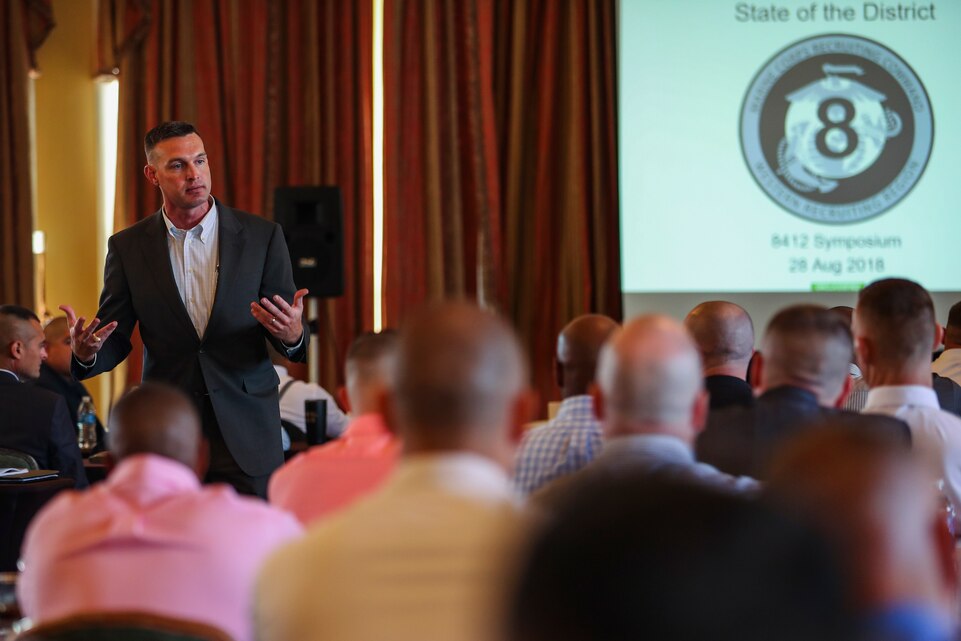 U.S. Marine Corps Lt. Col Taylor Young, 8th Marine Corps District recruiter operations officer, provides reflection on a record-breaking year and upcoming changes during a speech at the 8412 symposium in Galveston, Texas August 28, 2018. The Symposium brings 8th Marine Corps District career recruiters together to develop the mind, body and spirit of the individual career recruiter through sustainment training and advanced practices. (U.S. Marine Corps Photo by Sgt. Clarence A. Leake)