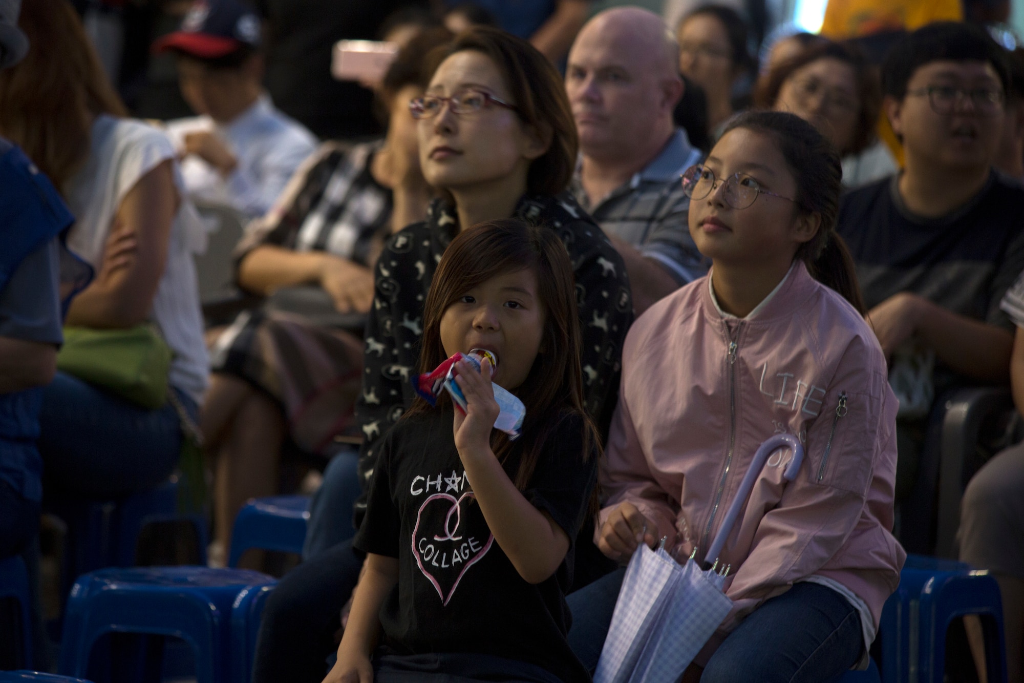 A young girl enjoys a snack while listening to the Pacific Brass from the Pacific Air Forces Band at Yokota Air Base, Tokyo, Japan, during the Seventh Air Force Friendship concert Aug. 26. The band, composed of five professional brass players, represented the unique tradition of military music and created an environment of friendship and fun. (U.S. Air Force photo by Master Sgt. Nadine Barclay)