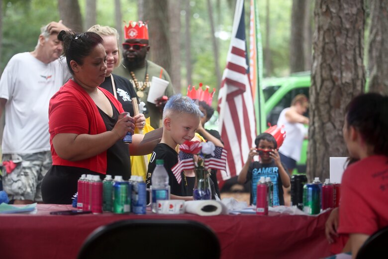 A volunteer at a booth sprays a child’s hair with temporary dye at a military appreciation day on Laurel Bay, Aug.
25. The event was held to foster cohesion between the Tri-command and the local community. The booth was
sponsored by Great Clips.