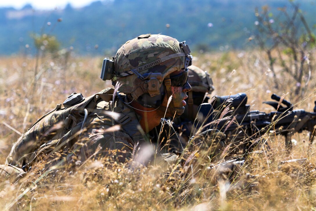 A soldier observes his team members maneuvering toward their objective during a live-fire exercise.