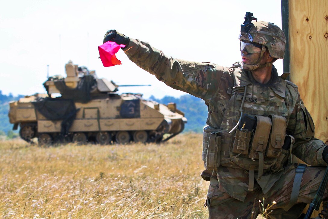 A soldier signals his gunner’s team to move forward toward their objective.